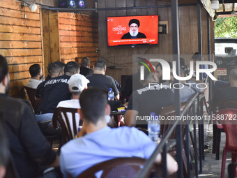 People watch Hezbollah leader Hassan Nasrallah on a television screen as he addresses the nation via video link at a cafe in the Shiyah neig...