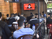 People watch Hezbollah leader Hassan Nasrallah on a television screen as he addresses the nation via video link at a cafe in the Shiyah neig...