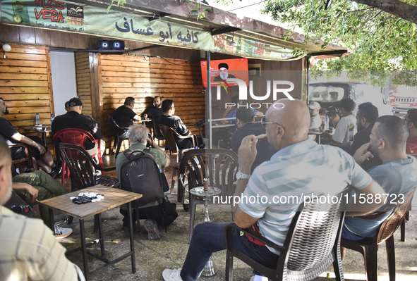 People watch Hezbollah leader Hassan Nasrallah on a television screen as he addresses the nation via video link at a cafe in the Shiyah neig...