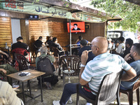 People watch Hezbollah leader Hassan Nasrallah on a television screen as he addresses the nation via video link at a cafe in the Shiyah neig...