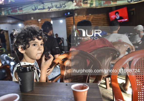 People watch Hezbollah leader Hassan Nasrallah on a television screen as he addresses the nation via video link at a cafe in the Shiyah neig...