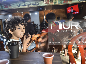 People watch Hezbollah leader Hassan Nasrallah on a television screen as he addresses the nation via video link at a cafe in the Shiyah neig...