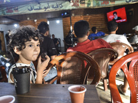 People watch Hezbollah leader Hassan Nasrallah on a television screen as he addresses the nation via video link at a cafe in the Shiyah neig...