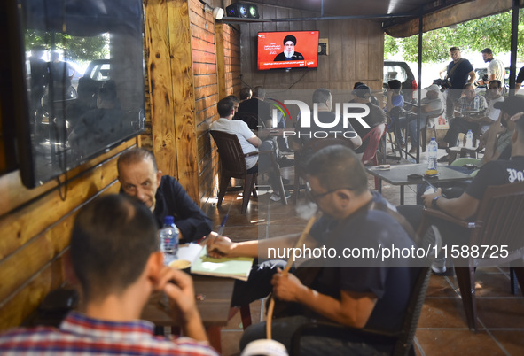 People watch Hezbollah leader Hassan Nasrallah on a television screen as he addresses the nation via video link at a cafe in the Shiyah neig...