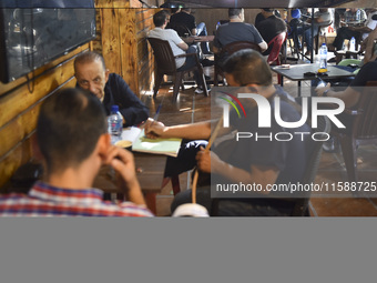 People watch Hezbollah leader Hassan Nasrallah on a television screen as he addresses the nation via video link at a cafe in the Shiyah neig...