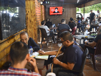 People watch Hezbollah leader Hassan Nasrallah on a television screen as he addresses the nation via video link at a cafe in the Shiyah neig...