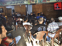 People watch Hezbollah leader Hassan Nasrallah on a television screen as he addresses the nation via video link at a cafe in the Shiyah neig...