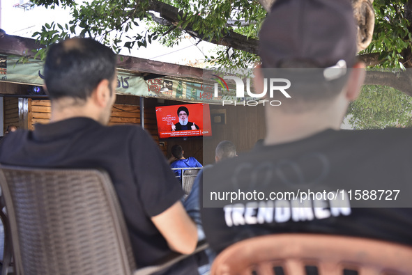 People watch Hezbollah leader Hassan Nasrallah on a television screen as he addresses the nation via video link at a cafe in the Shiyah neig...