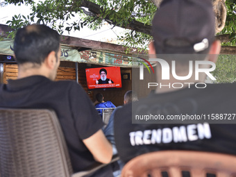 People watch Hezbollah leader Hassan Nasrallah on a television screen as he addresses the nation via video link at a cafe in the Shiyah neig...