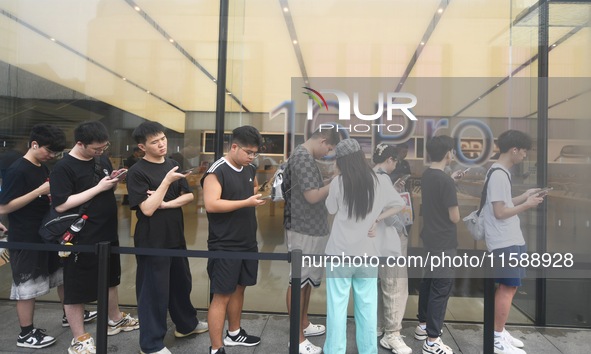 Customers line up outside the Apple flagship store as they wait to enter the store to buy the iPhone 16 in Hangzhou, China, on September 20,...