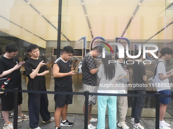 Customers line up outside the Apple flagship store as they wait to enter the store to buy the iPhone 16 in Hangzhou, China, on September 20,...