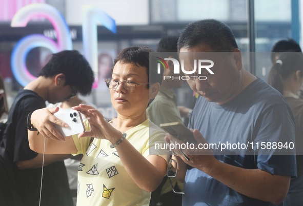 Customers experience an iPhone 16 at the Apple flagship store in Hangzhou, China, on September 20, 2024. 