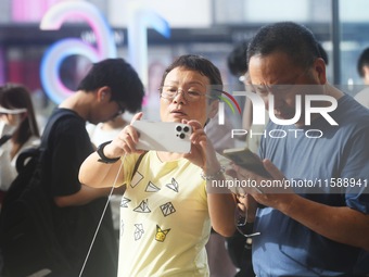 Customers experience an iPhone 16 at the Apple flagship store in Hangzhou, China, on September 20, 2024. (