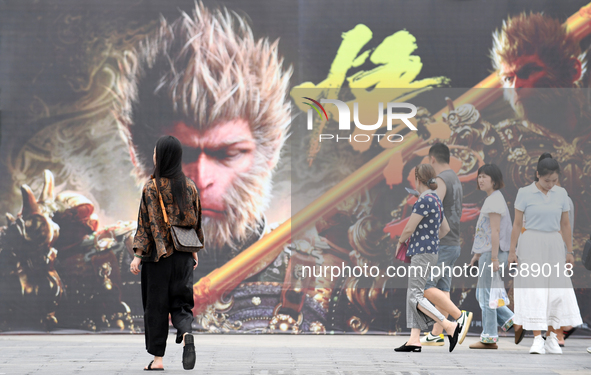 People walk past a poster promoting the Chinese 3A game Black Myth: Wukong in Renhuai, China, on September 15, 2024. 