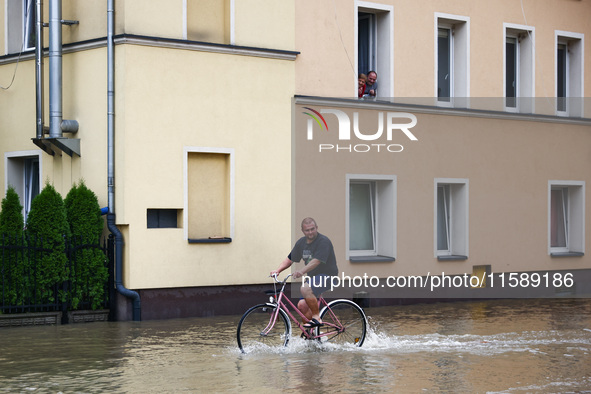 A resident rides a bicycle in the water after Nysa Klodzka river flooded town of Lewin Brzeski in southwestern Poland, on September 19th, 20...