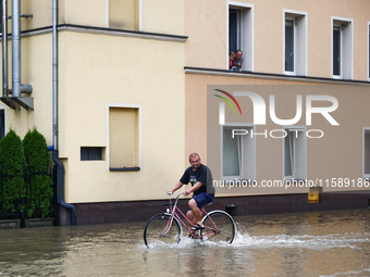 A resident rides a bicycle in the water after Nysa Klodzka river flooded town of Lewin Brzeski in southwestern Poland, on September 19th, 20...