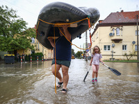 A man with a girl carries a raft after Nysa Klodzka river flooded town of Lewin Brzeski in southwestern Poland, on September 19th, 2024. Sto...