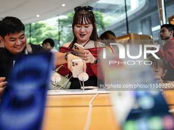 Customers try out the latest iPhone 16 models at an Apple store in Bangkok, Thailand, on September 20, 2024. Apple now makes available to co...