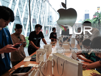 Customers try out the latest iPhone 16 models at an Apple store in Bangkok, Thailand, on September 20, 2024. Apple now makes available to co...