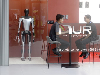 Electric cars and humanoid AI robots are displayed at a new Tesla store in Shanghai, China, on August 9, 2024. (