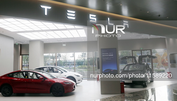 Electric cars and humanoid AI robots are displayed at a new Tesla store in Shanghai, China, on August 9, 2024. 