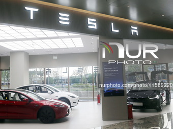 Electric cars and humanoid AI robots are displayed at a new Tesla store in Shanghai, China, on August 9, 2024. (