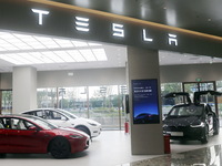 Electric cars and humanoid AI robots are displayed at a new Tesla store in Shanghai, China, on August 9, 2024. (