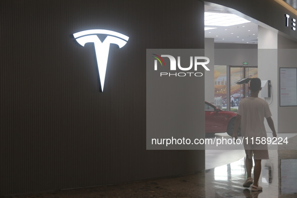 Electric cars and humanoid AI robots are displayed at a new Tesla store in Shanghai, China, on August 9, 2024. 