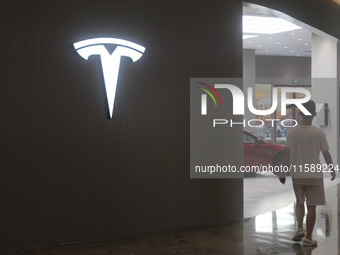 Electric cars and humanoid AI robots are displayed at a new Tesla store in Shanghai, China, on August 9, 2024. (