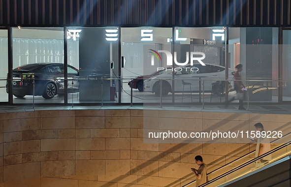 Electric cars and humanoid AI robots are displayed at a new Tesla store in Shanghai, China, on August 9, 2024. 