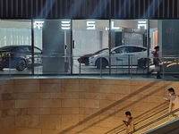 Electric cars and humanoid AI robots are displayed at a new Tesla store in Shanghai, China, on August 9, 2024. (