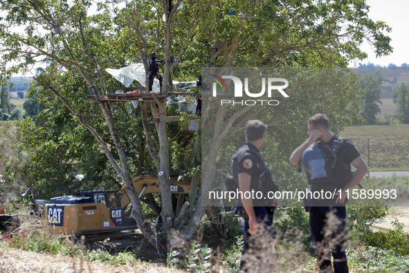 Gendarmes stand guard as members of the CNAMO unit try to convince 'Ecureuil' to stop their occupation of Zineb, an old walnut tree, while a...