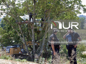 Gendarmes stand guard as members of the CNAMO unit try to convince 'Ecureuil' to stop their occupation of Zineb, an old walnut tree, while a...