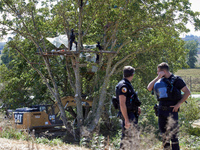 Gendarmes stand guard as members of the CNAMO unit try to convince 'Ecureuil' to stop their occupation of Zineb, an old walnut tree, while a...