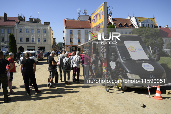 People queue for food at a World Central Kitchen truck in Glucholazy, Poland, on September 20, 2024. 