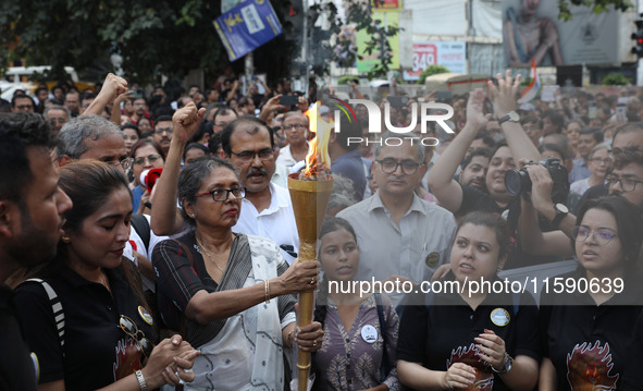 Doctors and citizens hold placards while marching with burning torches during a protest march and shout slogans, protesting against the rape...