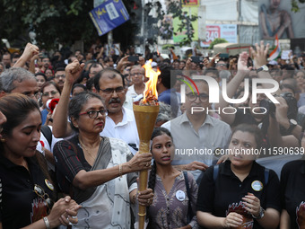 Doctors and citizens hold placards while marching with burning torches during a protest march and shout slogans, protesting against the rape...