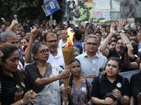 Doctors and citizens hold placards while marching with burning torches during a protest march and shout slogans, protesting against the rape...