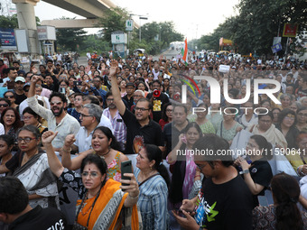 Doctors and citizens hold placards while marching with burning torches during a protest march and shout slogans, protesting against the rape...