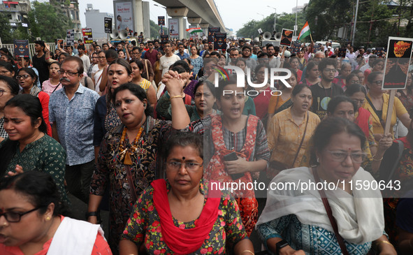 Doctors and citizens hold placards while marching with burning torches during a protest march and shout slogans, protesting against the rape...