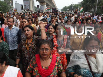 Doctors and citizens hold placards while marching with burning torches during a protest march and shout slogans, protesting against the rape...