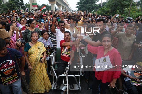 A handicapped man shouts slogans and holds a burning torch while doctors and citizens hold placards and march with burning torches during a...