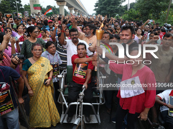 A handicapped man shouts slogans and holds a burning torch while doctors and citizens hold placards and march with burning torches during a...