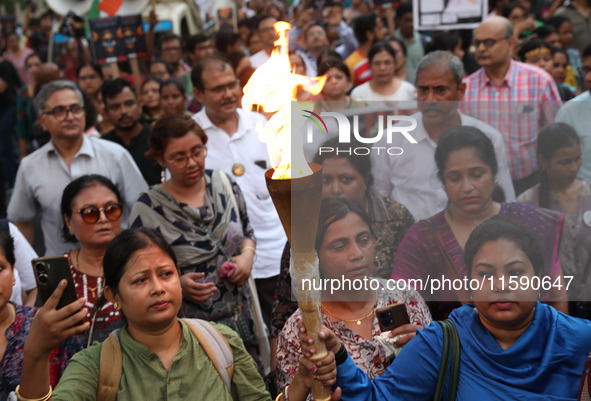 Doctors and citizens hold placards while marching with burning torches during a protest march and shout slogans, protesting against the rape...