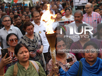 Doctors and citizens hold placards while marching with burning torches during a protest march and shout slogans, protesting against the rape...