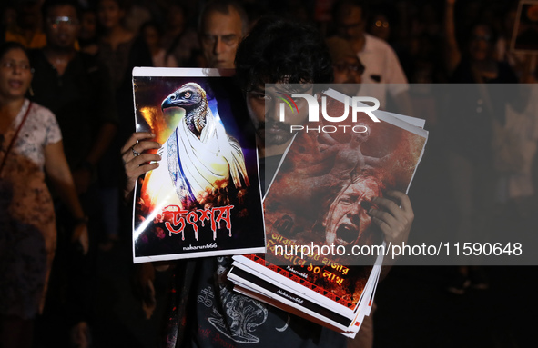 A man holds placards while doctors and citizens hold placards and march with burning torches during a protest against the rape and murder of...