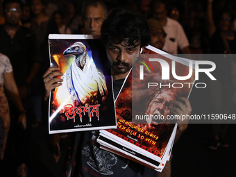 A man holds placards while doctors and citizens hold placards and march with burning torches during a protest against the rape and murder of...