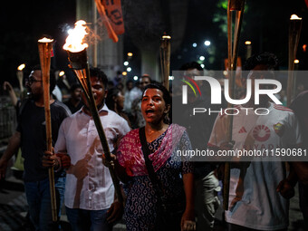 People hold a procession with torches to protest the recent violent clashes and counter-clashes between the local indigenous population and...