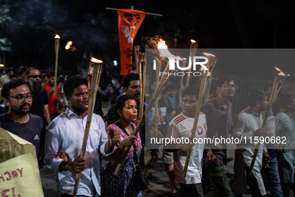 People hold a procession with torches to protest the recent violent clashes and counter-clashes between the local indigenous population and...