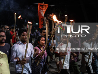 People hold a procession with torches to protest the recent violent clashes and counter-clashes between the local indigenous population and...